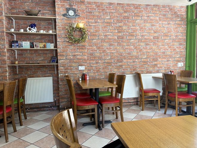 Wooden tables and red-cushioned chairs against a brick feature wall