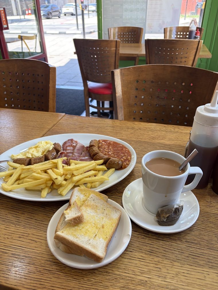 A cooked breakfast with chips and a mug of tea by the window